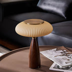 Brass-topped shade of this Clérachic table lamp on a round table, with a leather sofa behind and magazines on the surface.