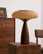 Unlit Clérachic ribbed lamp on a rough wooden block, its cinnamon shade and brass top against a walnut drawer unit.