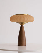 Clérachic table lamp on a white table, unlit, the ribbed cinnamon shade above a brass collar and a small brass button.