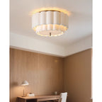 A Clérachic ceiling light lit in a room with oak-panelled walls, a wooden desk and a small table lamp in the distance.