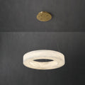 Clérachic ring chandelier hung low on slim cables, warm light washing through the stone band and brass canopy.