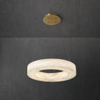 Clérachic ring chandelier hung low on slim cables, warm light washing through the stone band and brass canopy.