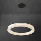 Clérachic ring chandelier viewed edge-on, the slim alabaster hoop reading as one continuous carved band.