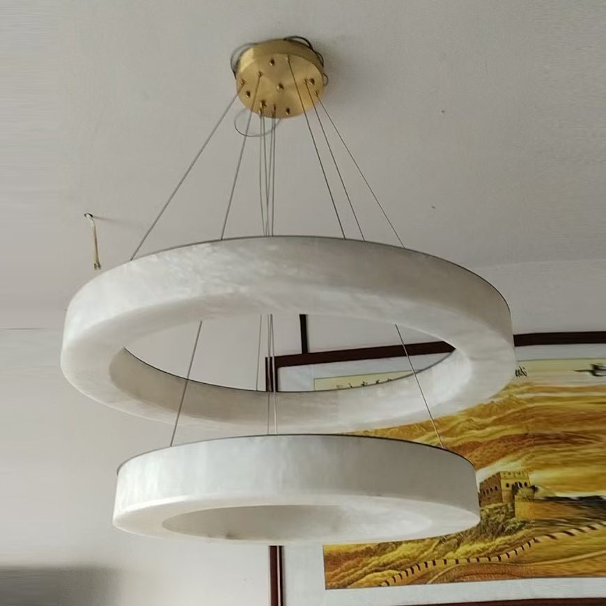 Clérachic two-ring chandelier in a lived-in room, brass canopy on a white ceiling above a framed landscape.