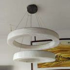 The Clérachic two-ring chandelier with black canopy, the stacked hoops casting a broad halo across the ceiling.