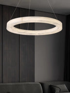 The Clérachic chandelier in a dark panelled room, the lit alabaster ring floating above a low sofa.