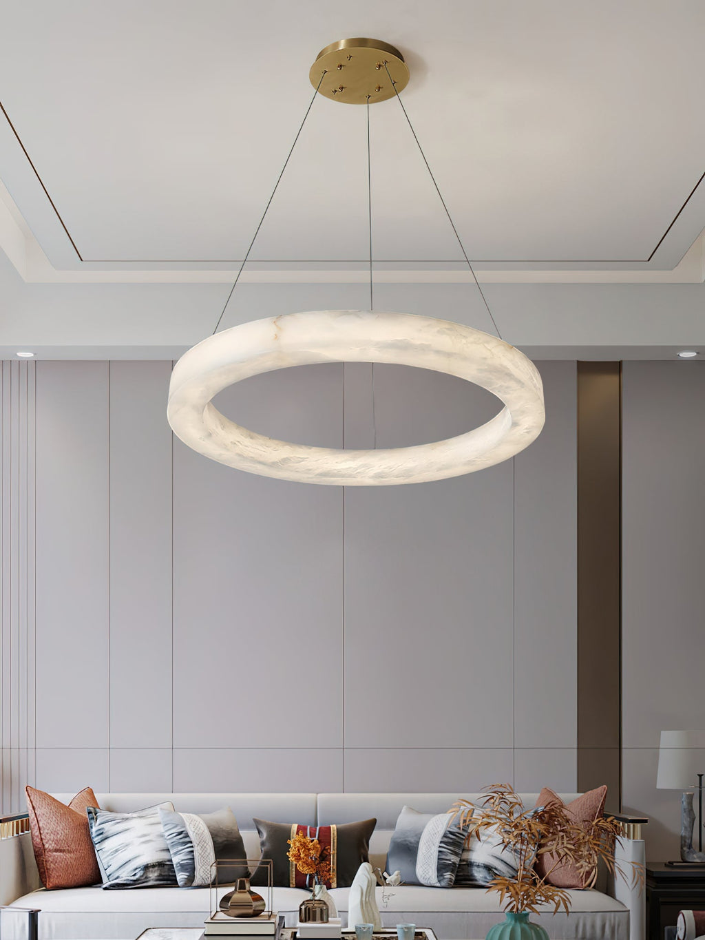 Clérachic chandelier hung over a bright living room, the wide alabaster ring balancing a long pale sofa.