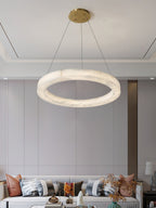 Clérachic chandelier hung over a bright living room, the wide alabaster ring balancing a long pale sofa.