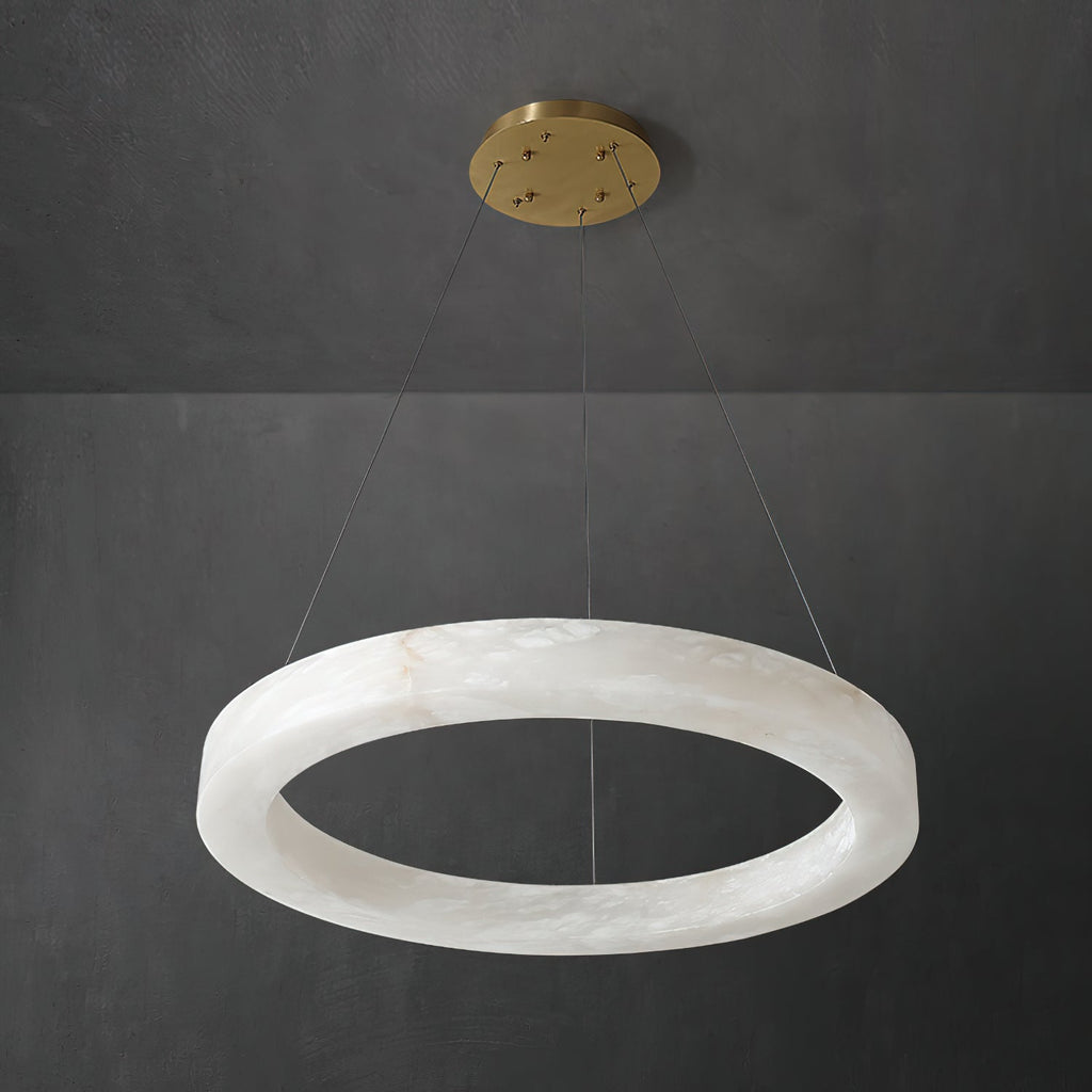 The Clérachic chandelier shot at an angle, alabaster hoop and brass canopy read against dark concrete.