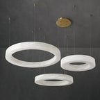 Clérachic chandelier in a three-ring layout, brass canopy feeding six cables down to the alabaster hoops.