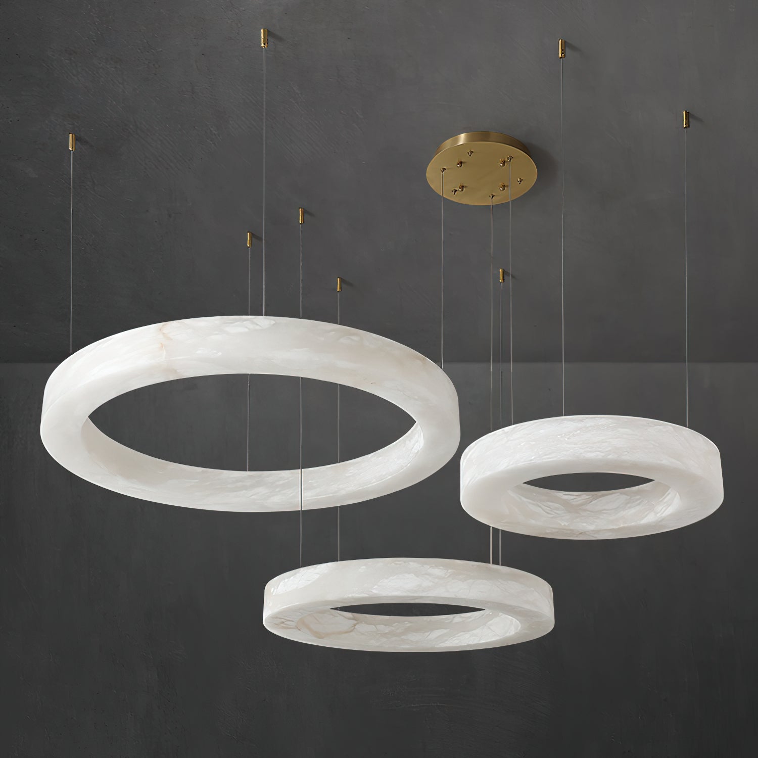 Clérachic chandelier in a three-ring layout, brass canopy feeding six cables down to the alabaster hoops.