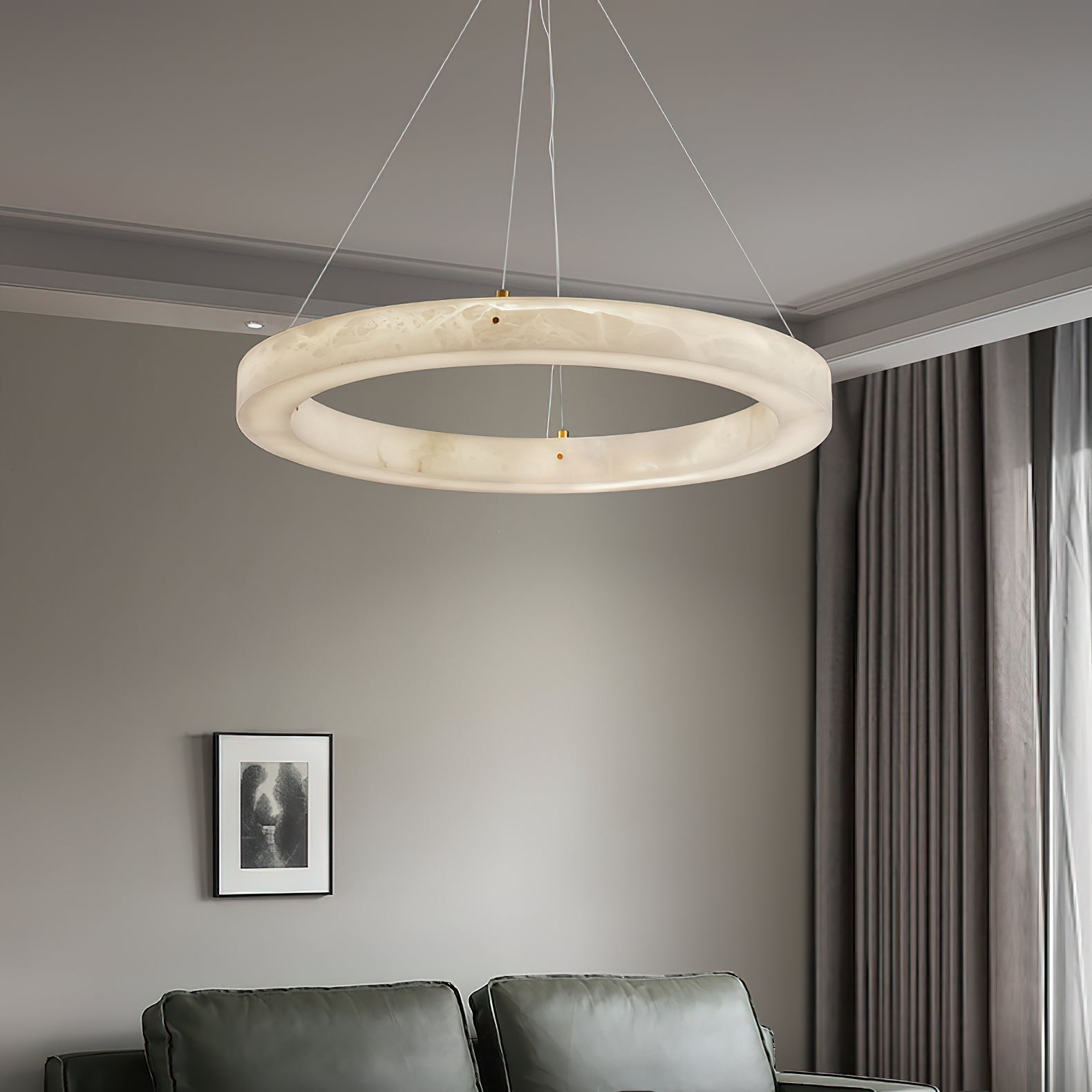 The Clérachic ring chandelier in a furnished sitting room, warm light spilling down over a green sofa.