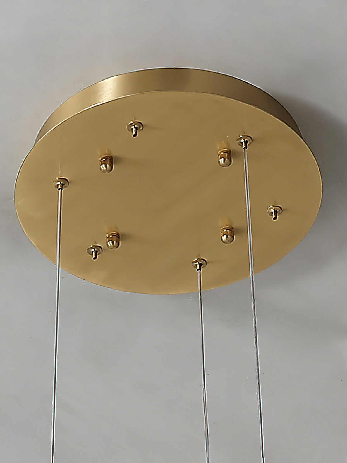 Clérachic brass ceiling canopy close-up, six cable grips and fixing screws set into the round plate.