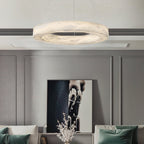 Clérachic ring chandelier lit above a panelled living room, its halo of light picked up by green cushions.