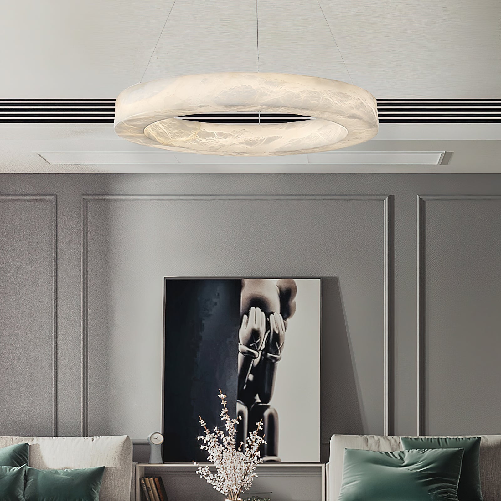 Clérachic ring chandelier lit above a panelled living room, its halo of light picked up by green cushions.