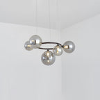 A Clérachic ring-frame pendant with 5 smoked mirrored glass globes hangs from thin cables in a bright corner room.