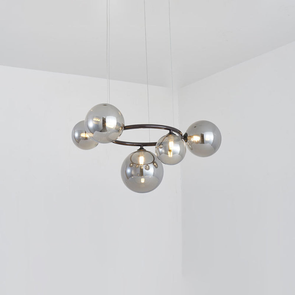 A Clérachic ring-frame pendant with 5 smoked mirrored glass globes hangs from thin cables in a bright corner room.