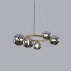 Studio view of the brass Clérachic ring-frame pendant fitted with 5 smoked mirrored glass globes on a gray backdrop.