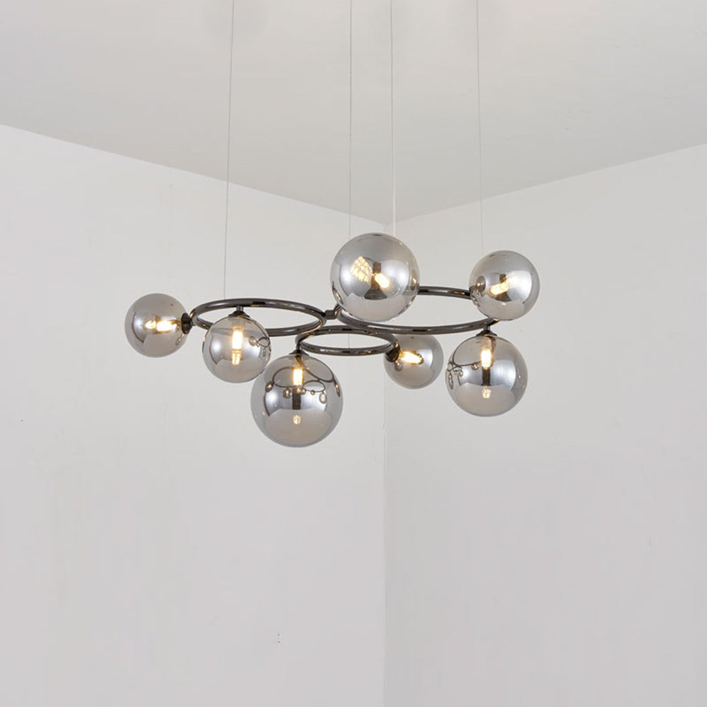 Seven smoked mirrored glass globes ring the black frame of this Clérachic pendant, lit in a plain corner room.
