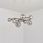 Seven smoked mirrored glass globes ring the black frame of this Clérachic pendant, lit in a plain corner room.