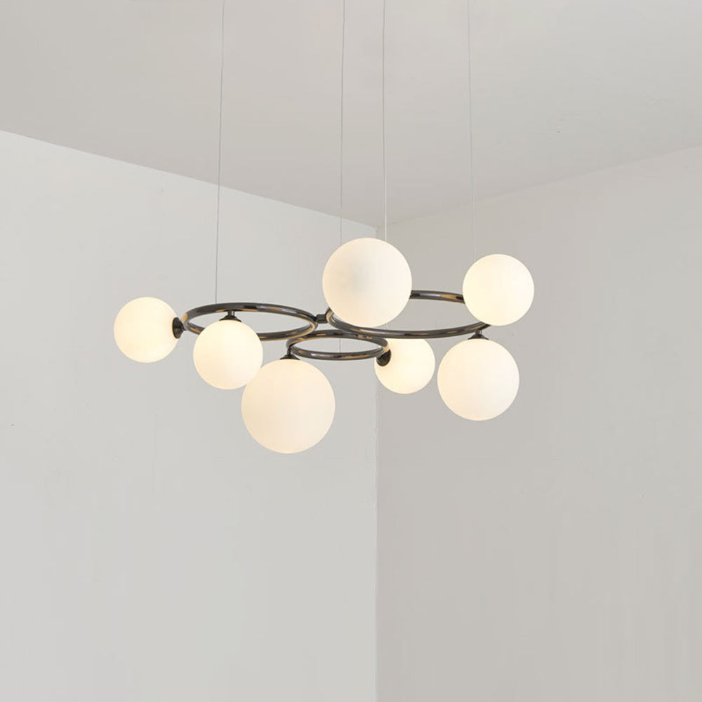 Seven glowing opal glass globes ring the black frame of this Clérachic pendant in a plain corner room.
