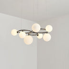 Seven glowing opal glass globes ring the black frame of this Clérachic pendant in a plain corner room.