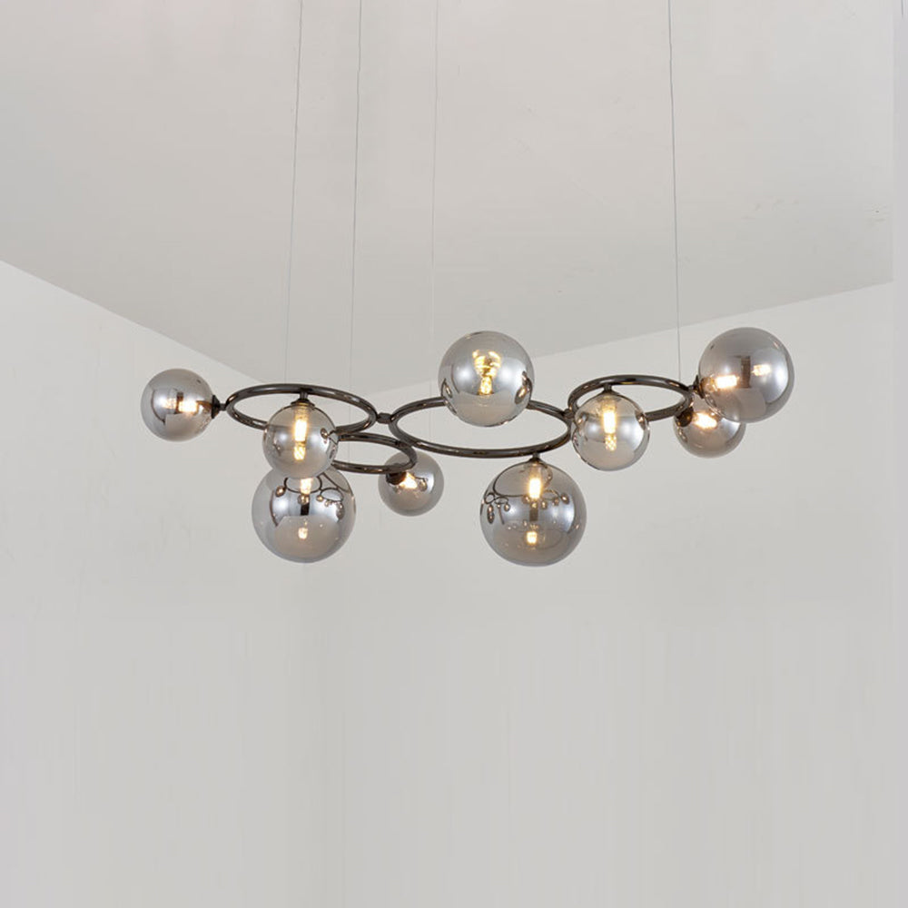 Nine smoked mirrored glass globes cluster around the black frame of this Clérachic pendant in a corner room.