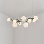 Nine glowing opal glass globes cluster around the black frame of this Clérachic pendant in a corner room.