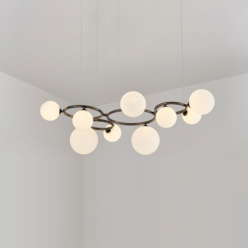 Nine glowing opal glass globes cluster around the black frame of this Clérachic pendant in a corner room.