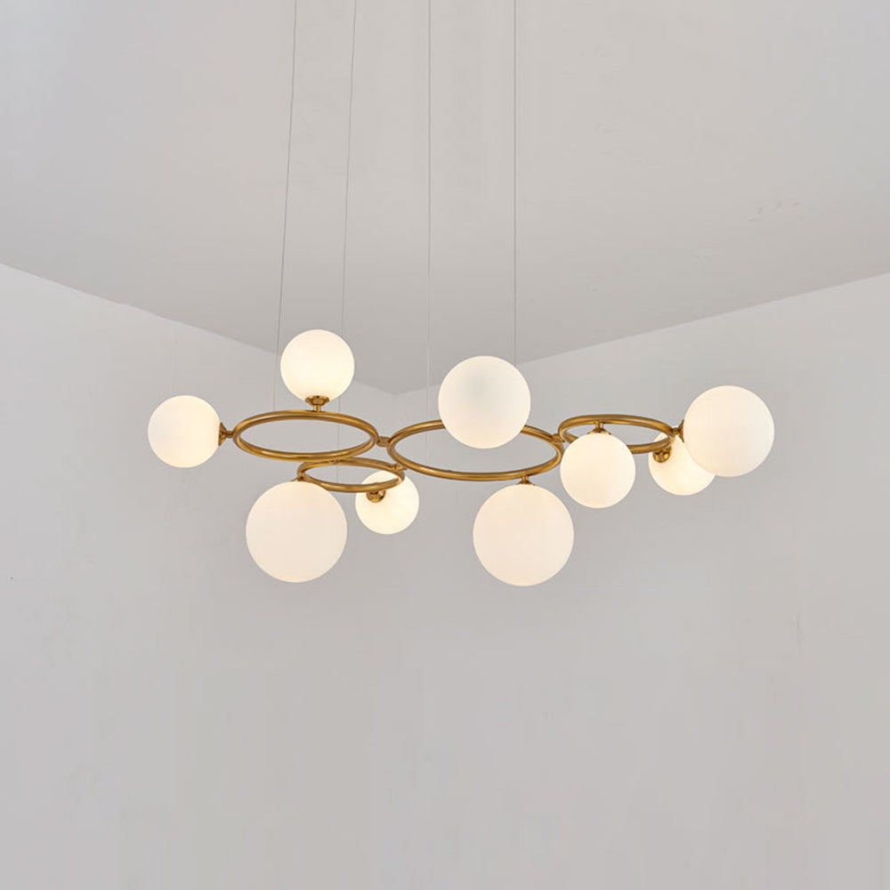 The brass Clérachic ring-frame pendant carries 9 glowing opal glass globes across its double ring frame.
