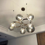 Upward angle on the Clérachic ring-frame pendant showing its translucent glass globes and three-cable ceiling mount.