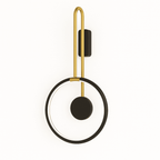 Clérachic black ring wall light with a brass-toned U-shaped arm and a black disc, lit with a thin inner glow on white.