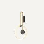 Clérachic wall light with a clear fluted acrylic ring, black disc and brass-toned U-shaped arm, shown on an off-white ground.