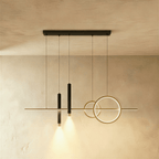 Clérachic pendant light with a gold bar and rings and two black spot cylinders hanging from a black canopy bar.