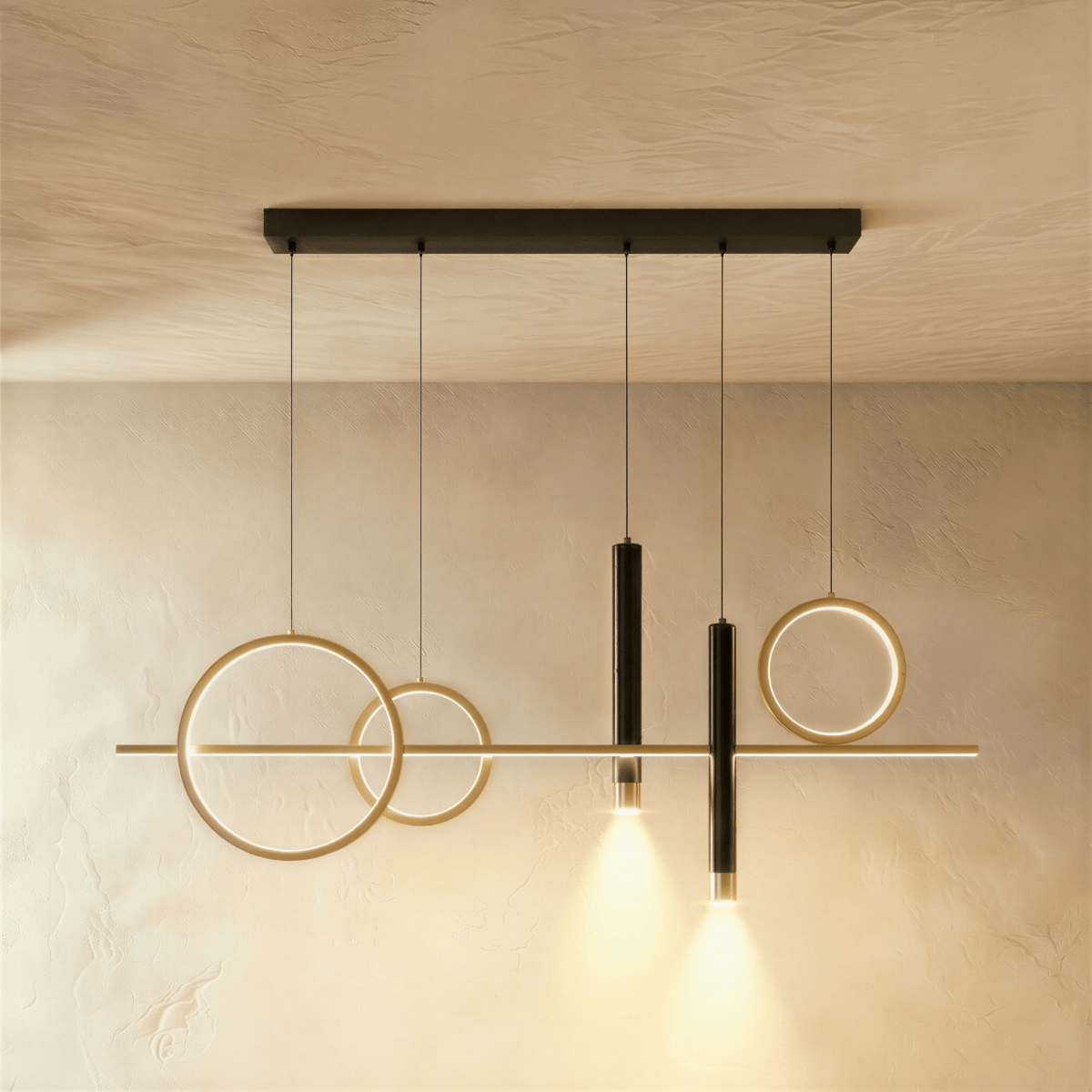 Clérachic mirrored layout pendant with two gold rings left, a ring right and two black spot cylinders on a limewash wall.