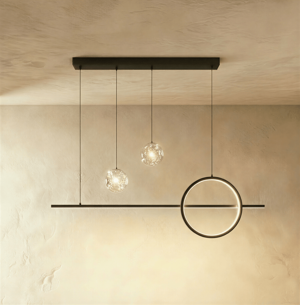 Clérachic black pendant light with a shorter bar, one ring and two clear sparkling glass globes on a limewash wall.