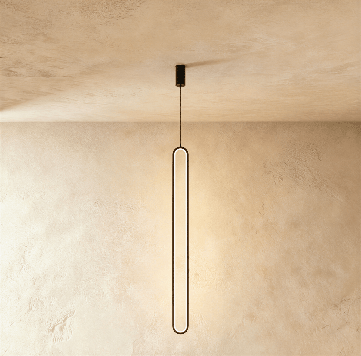 Clérachic slim black stadium-shaped LED loop pendant hanging long from a small black canopy against limewash.