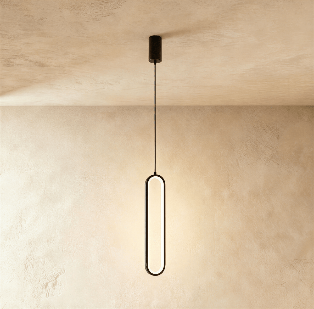 Clérachic compact black stadium-shaped LED loop pendant on a short black cord and round canopy, on a limewash wall.