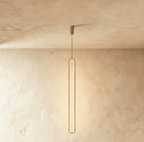 Clérachic slim gold stadium-shaped LED loop pendant hanging long from a small gold canopy against limewash.