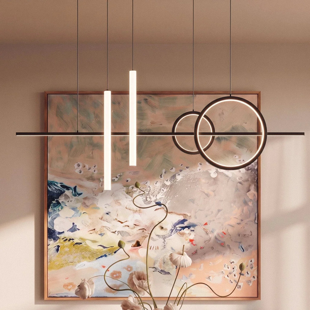 Close view of the Clérachic black pendant light, glowing rings and frosted tubes in front of a large abstract painting.