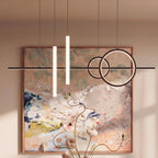 Close view of the Clérachic black pendant light, glowing rings and frosted tubes in front of a large abstract painting.