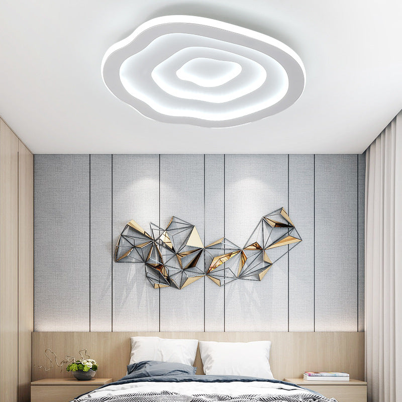The Clérachic Ripple Spiral ceiling light above a bedroom, layered rings echoing the wall artwork.