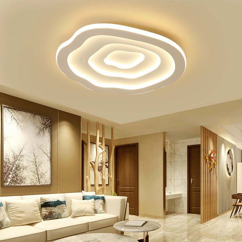 Clérachic Ripple Spiral ceiling light glowing over a pale living room with a low linen sofa.