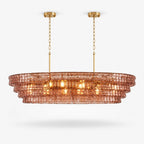 Rose-pink glass tiers on this Clérachic linear chandelier, hung from two gold canopies on a plain white backdrop.