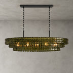 This Clérachic chandelier in green glass hangs from a black long canopy on black chains, lit, on a plain grey backdrop.
