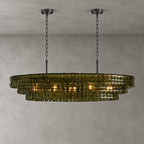 Green glass on this Clérachic chandelier, hung from two black round canopies and black chains against a grey backdrop.