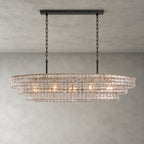 A clear-glass Clérachic chandelier with a black long canopy and black chains, glowing softly on a grey backdrop.