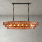 Rose-pink glass tiers on this Clérachic chandelier, hung from a black long canopy with black chain, lit on a grey backdrop.