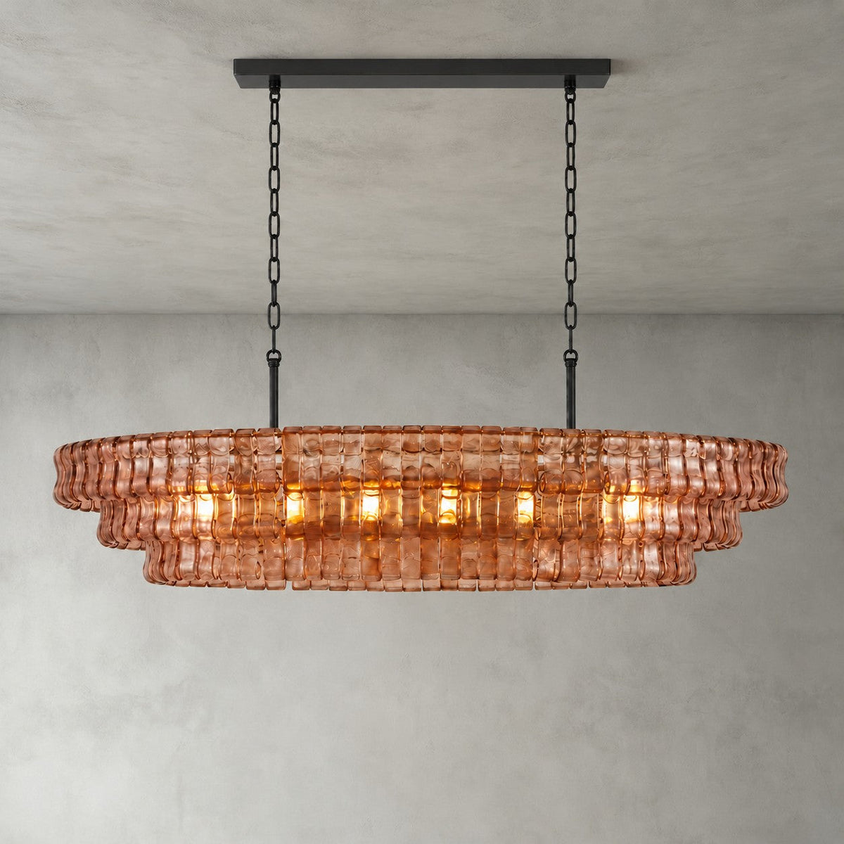 Rose-pink glass tiers on this Clérachic chandelier, hung from a black long canopy with black chain, lit on a grey backdrop.