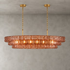 This Clérachic chandelier in rose-pink glass hangs from two gold round canopies with slim stems against a grey wall.
